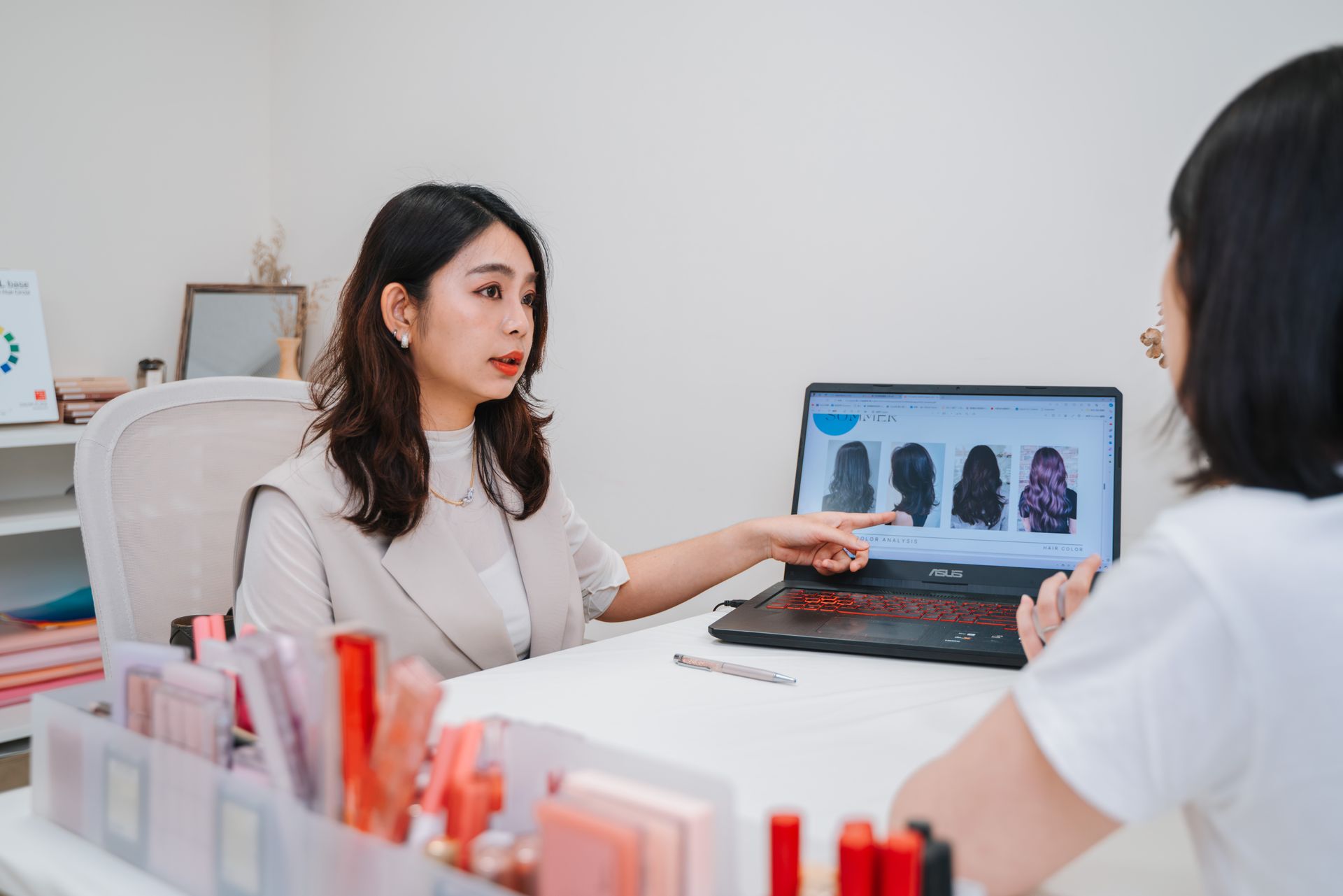 一位女士拿著筆記型電腦坐在桌旁，正在與另一位女士交談。