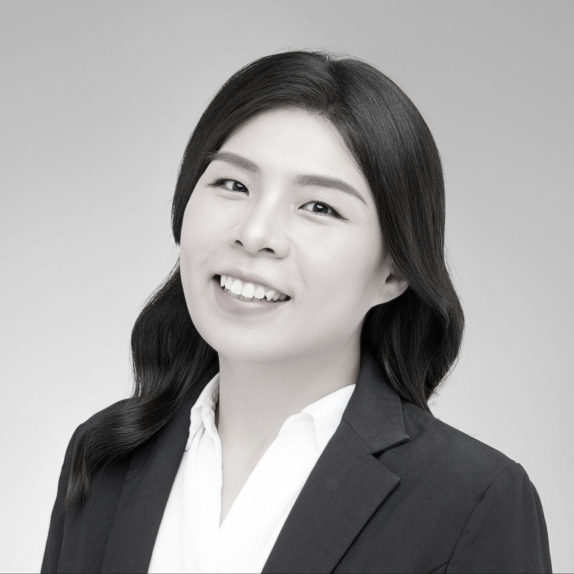 黑白照片中,一名身穿白色夾克的女子微笑著。