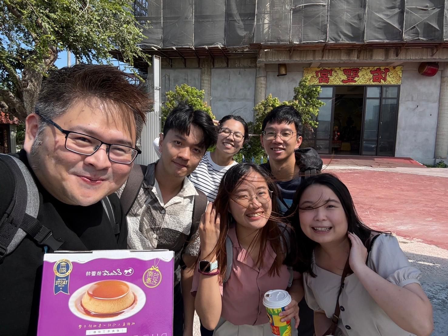 一群人在一棟大樓前擺姿勢拍照。