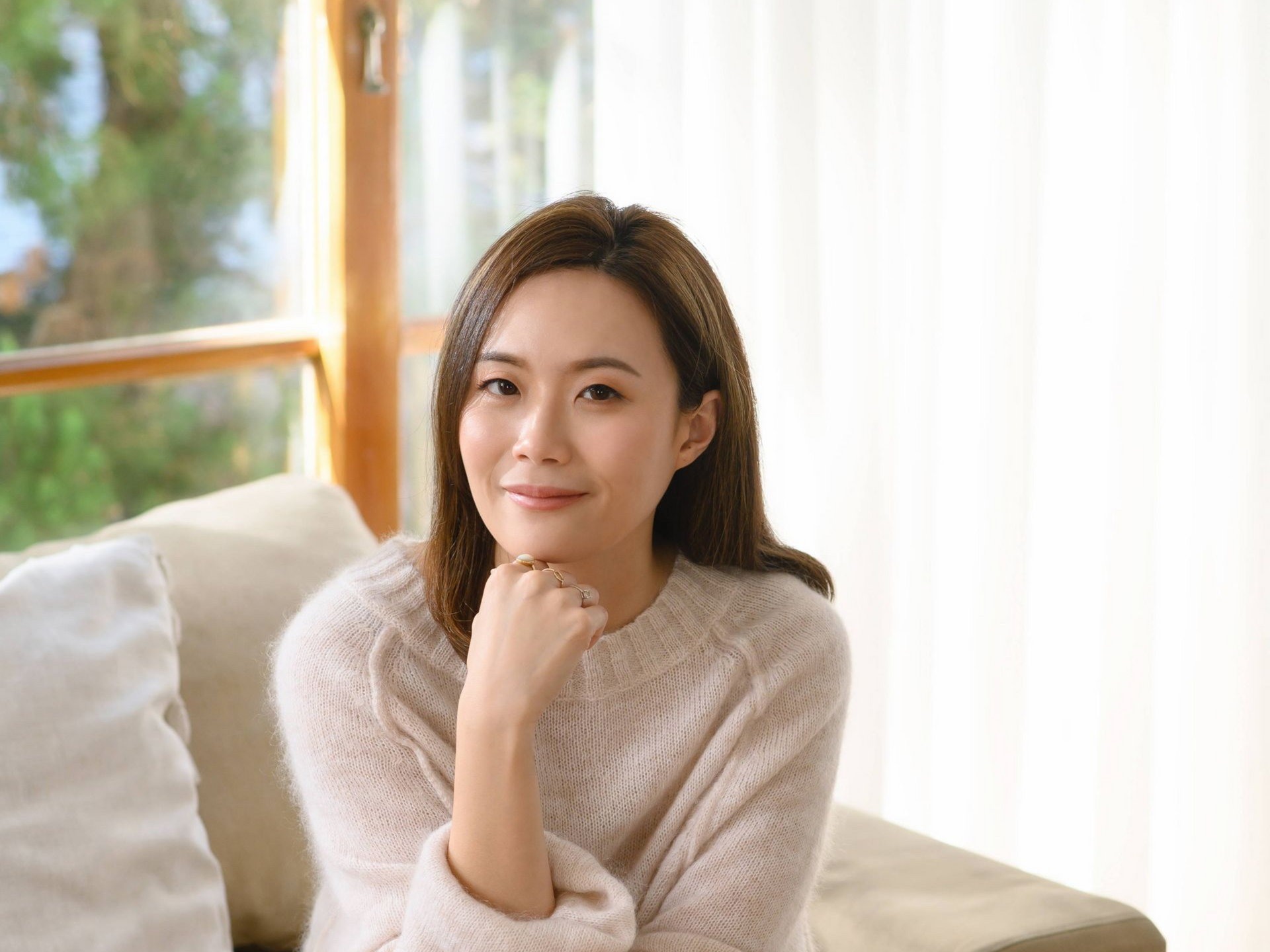 一個女人坐在桌邊,手裡拿著一杯咖啡。