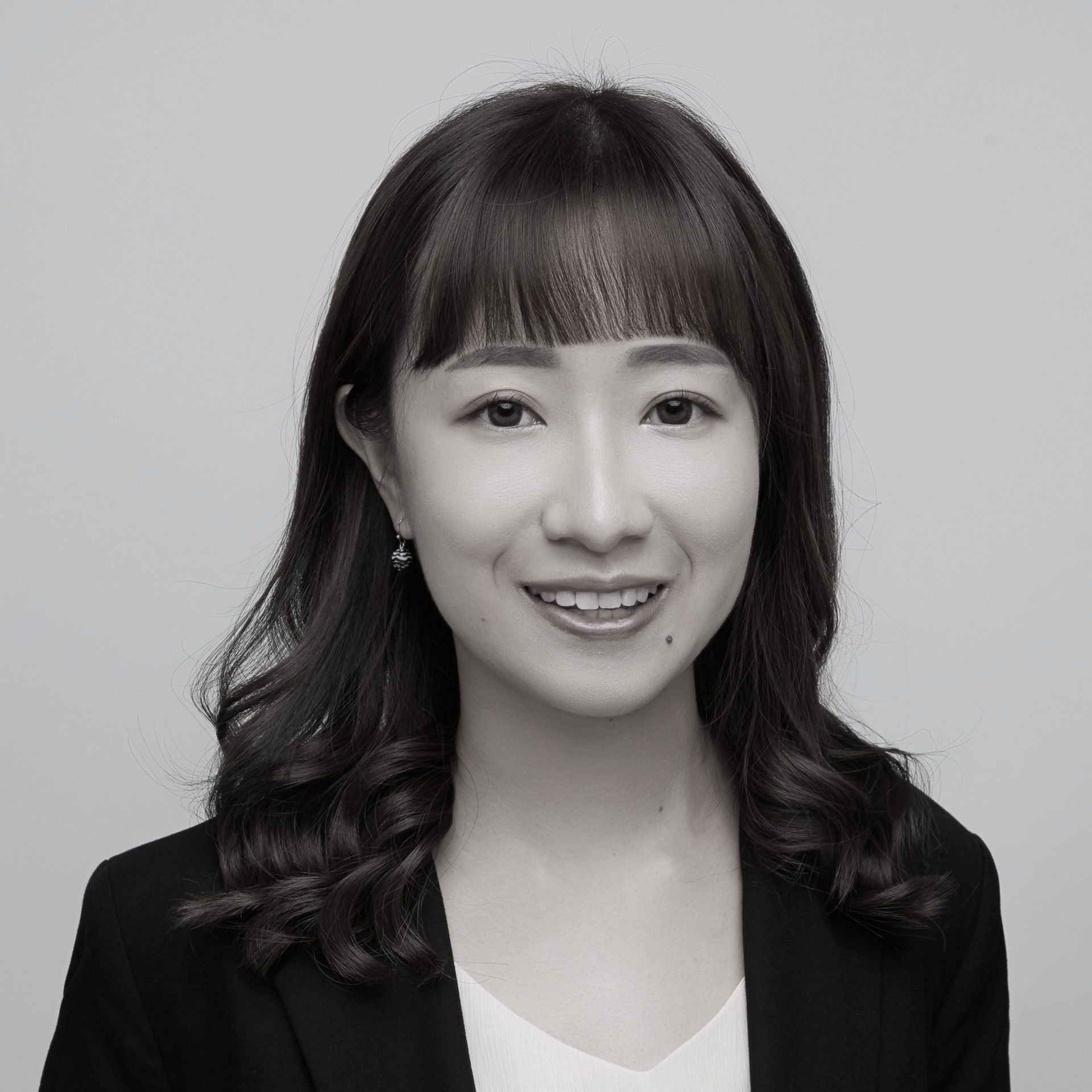 黑白照片中,一名身穿白色夾克的女子微笑著。