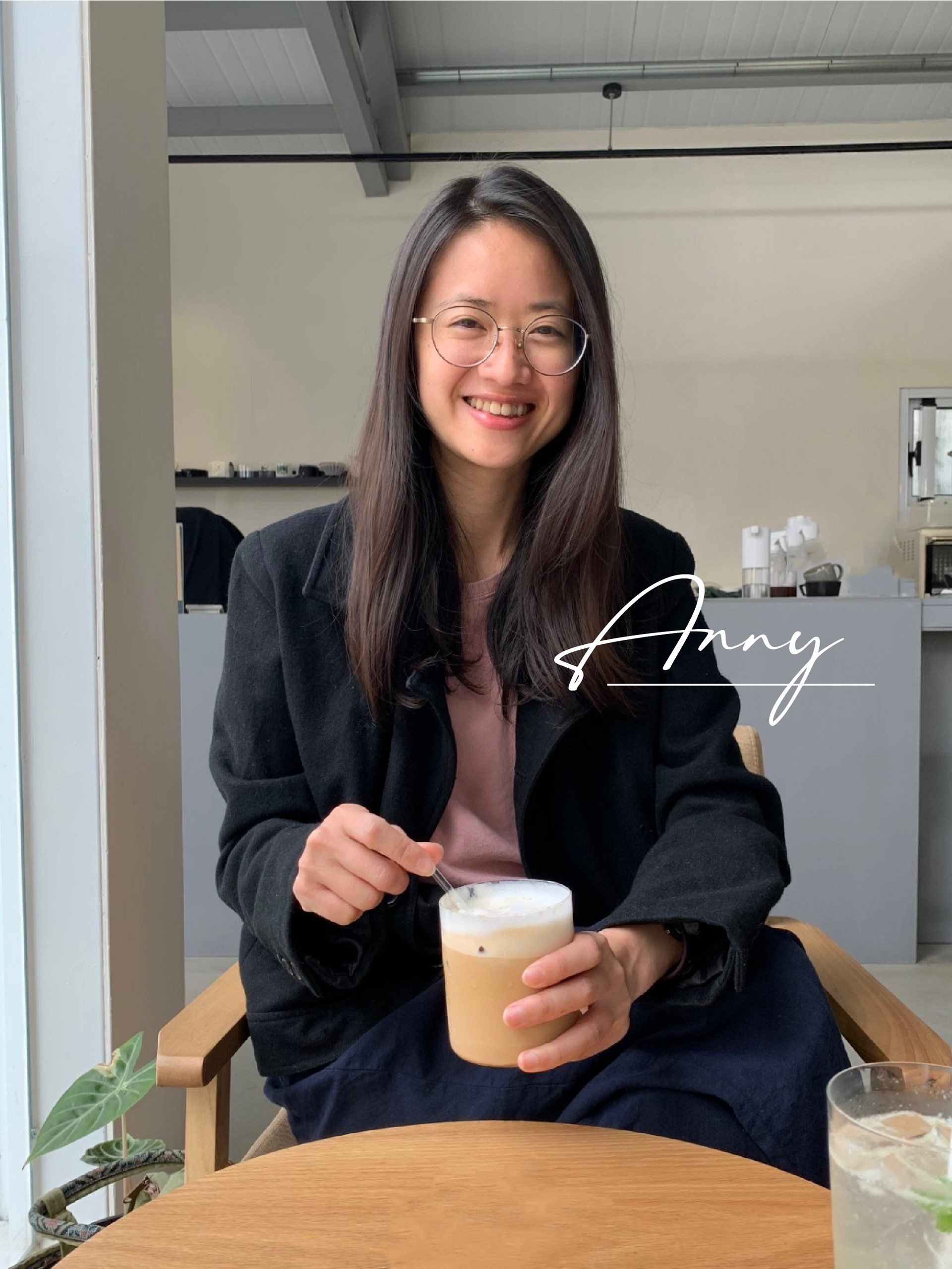 一個女人坐在桌邊，手裡拿著一杯咖啡。