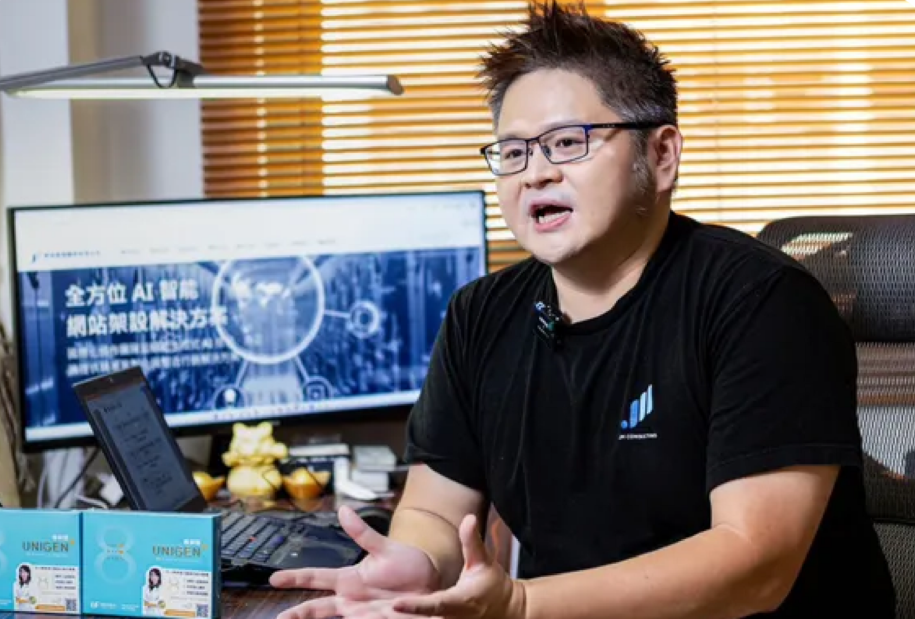 一個戴著眼鏡的男人坐在辦公桌前的電腦前。