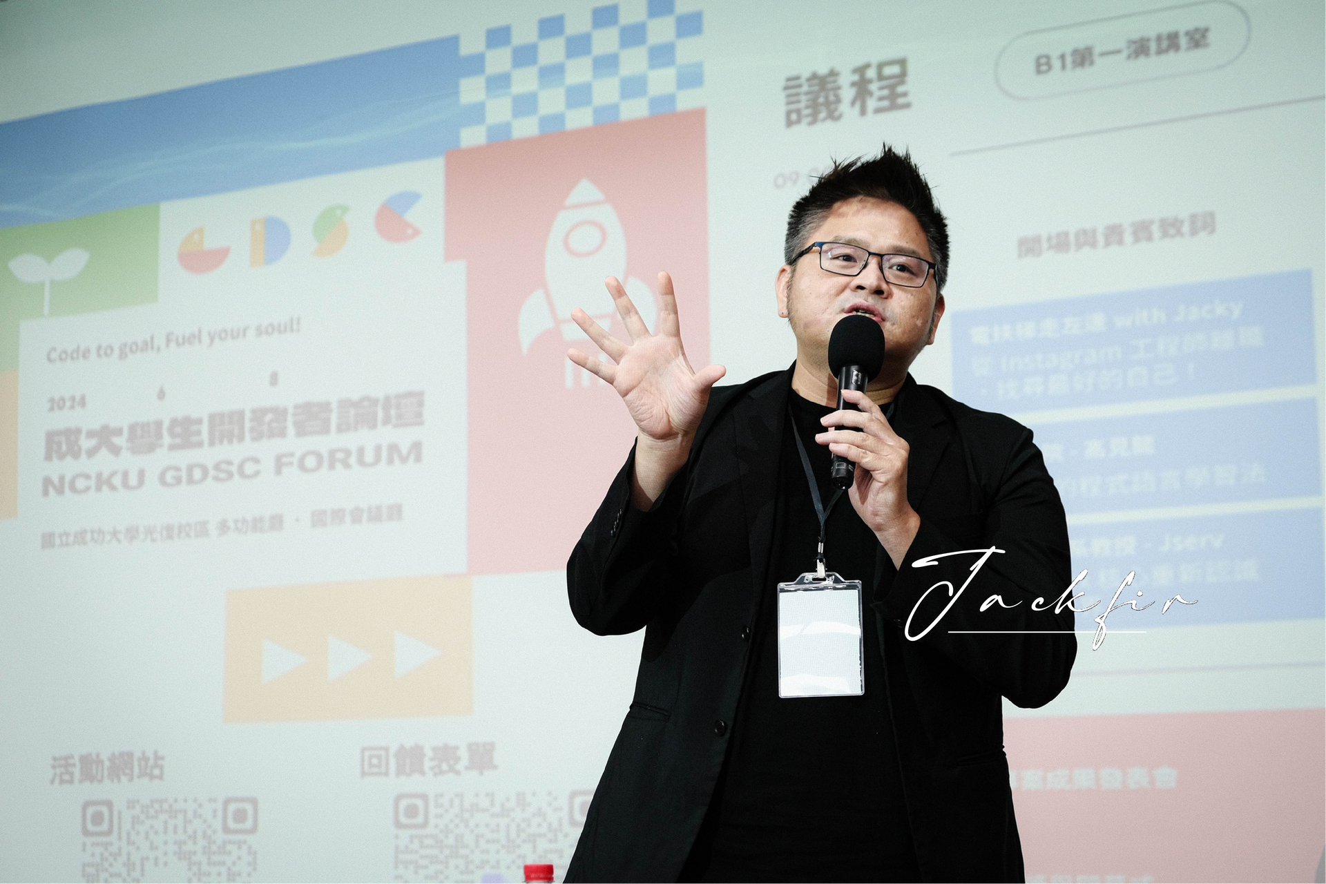 一個男人拿著麥克風站在大螢幕前。