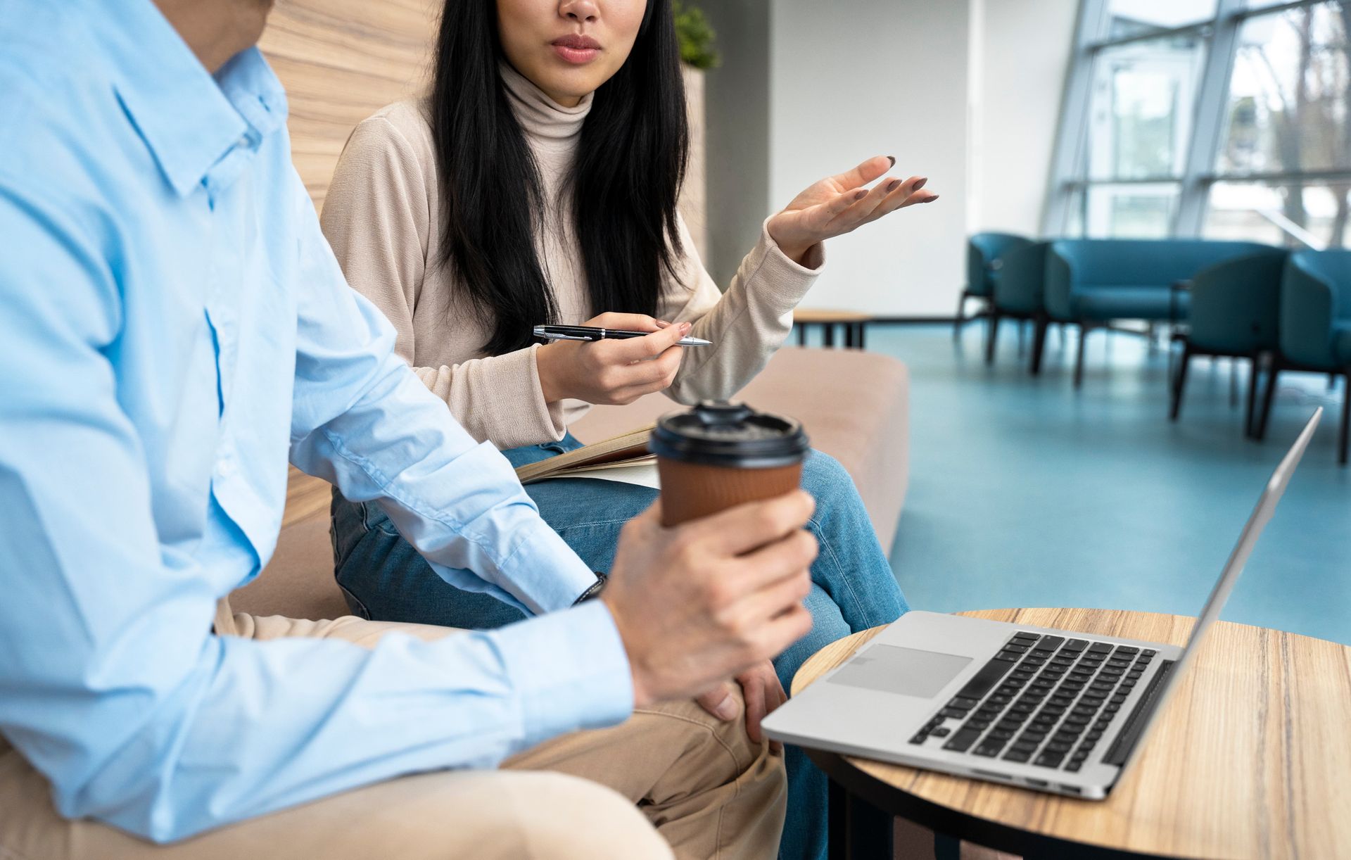 一個男人和一個女人坐在一張桌子旁,手裡拿著一台筆記型電腦。