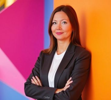 A woman in a suit is leaning against a wall with her arms crossed.