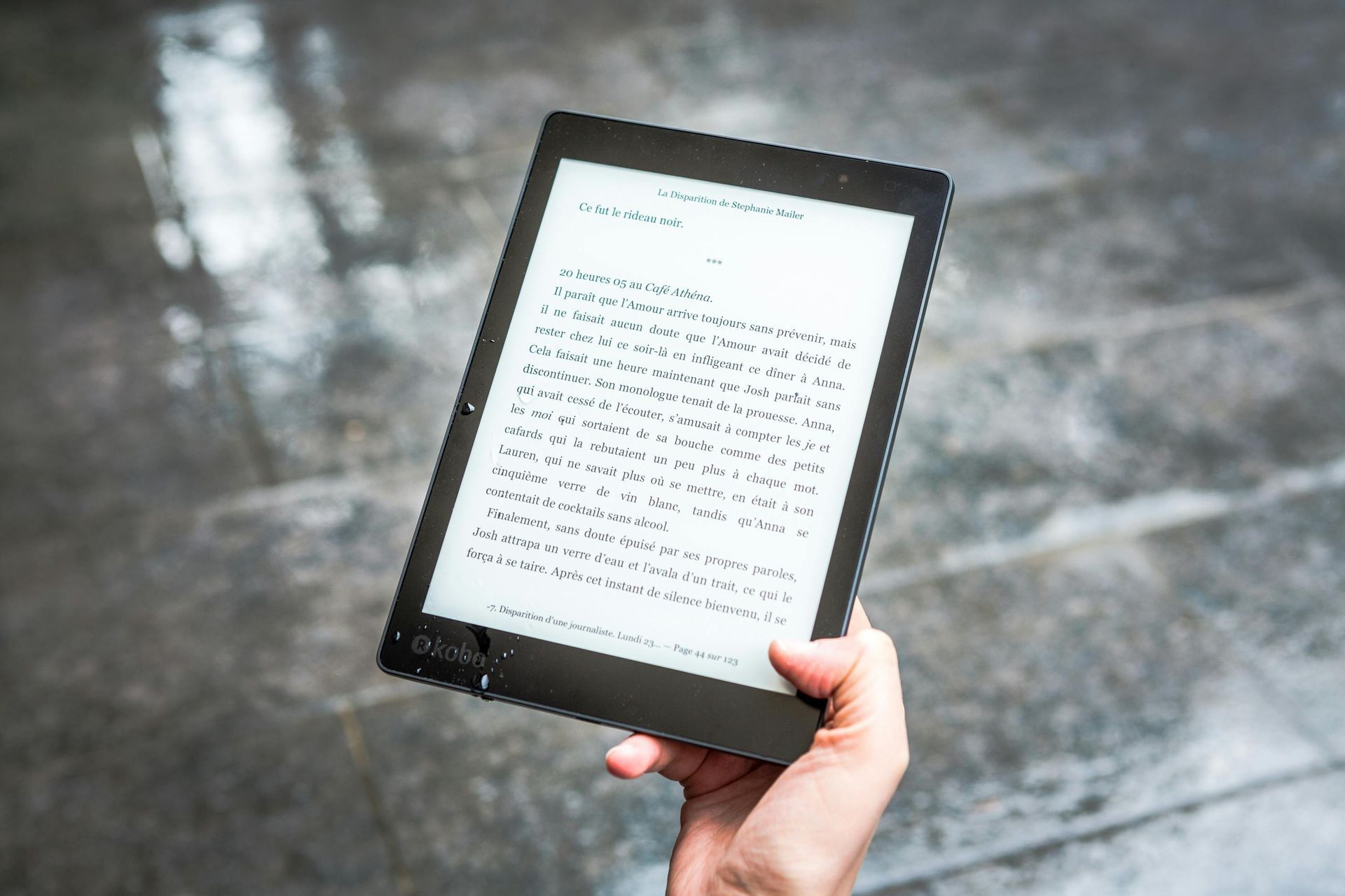 A person is holding a tablet in their hand in the rain.