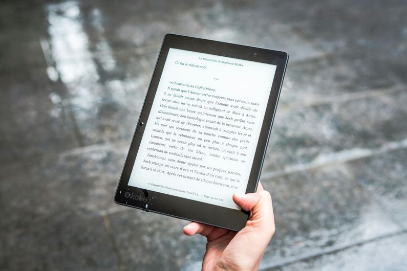 A person is holding a tablet in their hand in the rain.