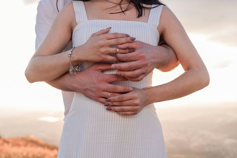 A man is hugging a woman in a white dress.