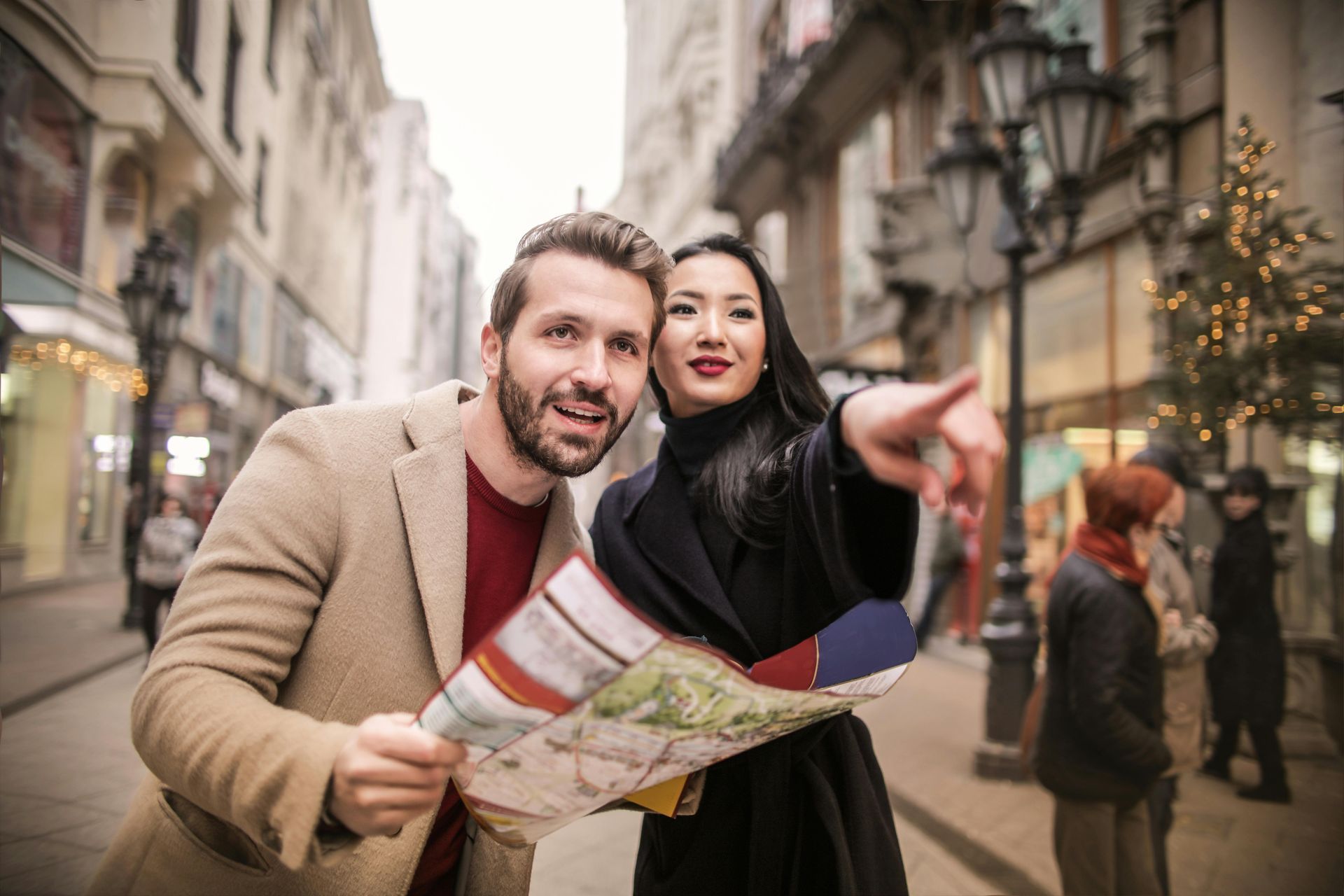 A man and a woman are looking at a map on a city street.