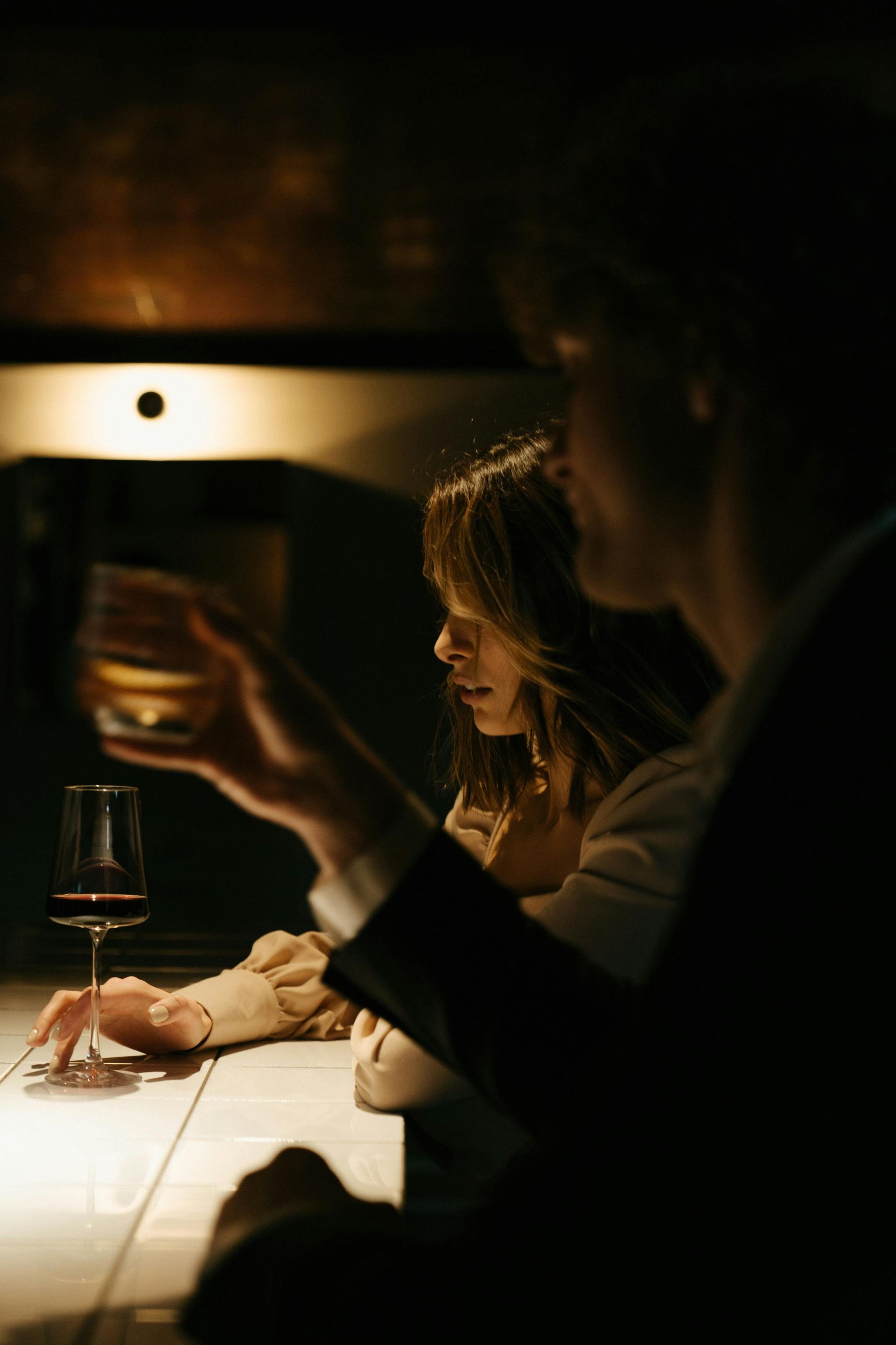 A man and a woman are sitting at a table drinking wine.