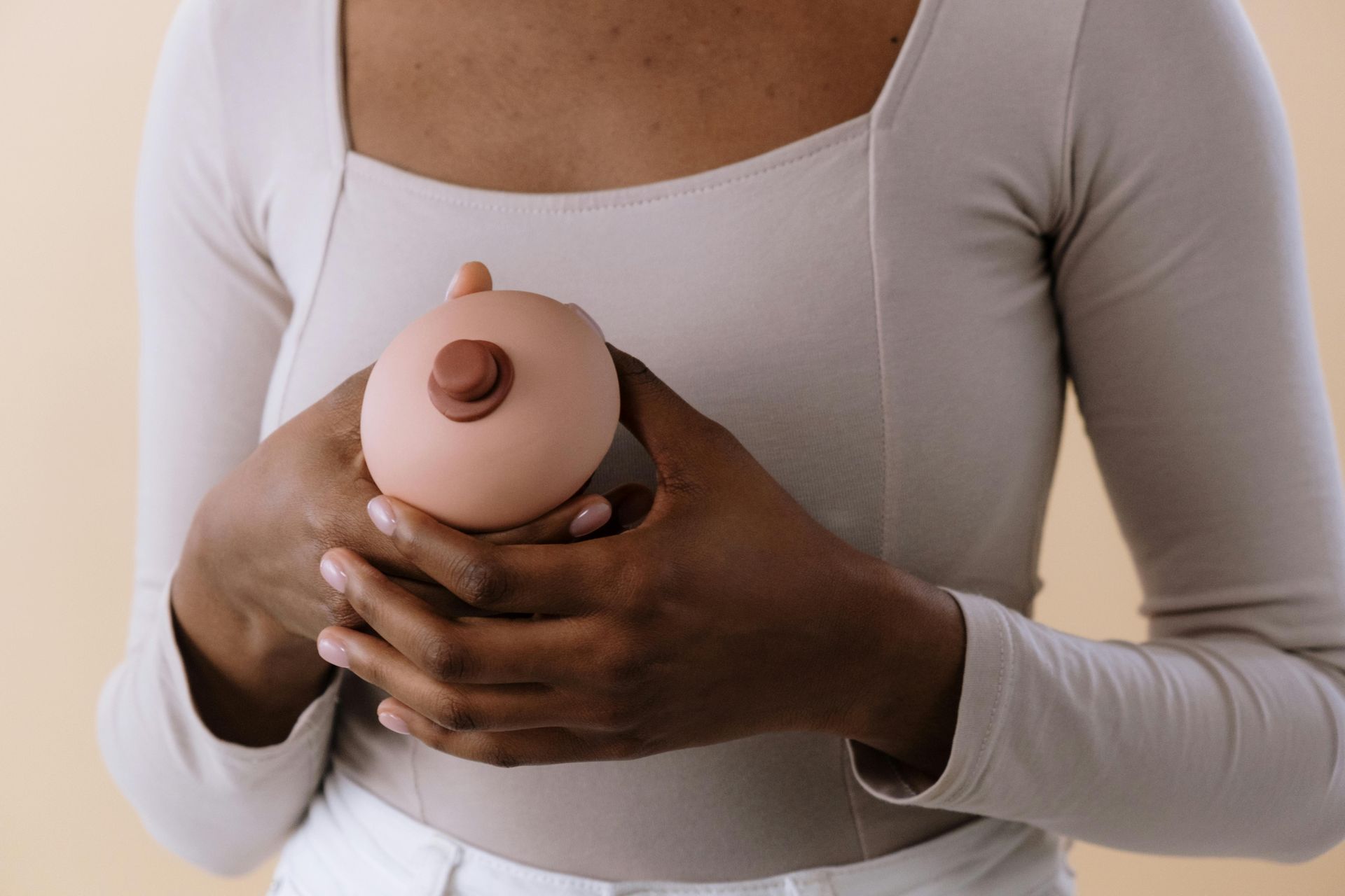 A woman is holding a mannequin breast in her hands.