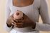 A woman is holding a mannequin breast in her hands.