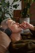 An older woman is laying on a couch wearing headphones.