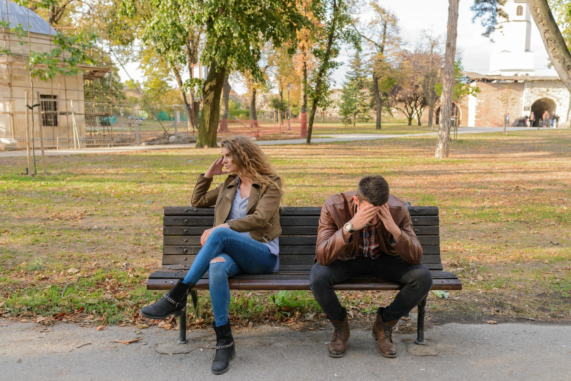 A man and a woman are sitting on a park bench.