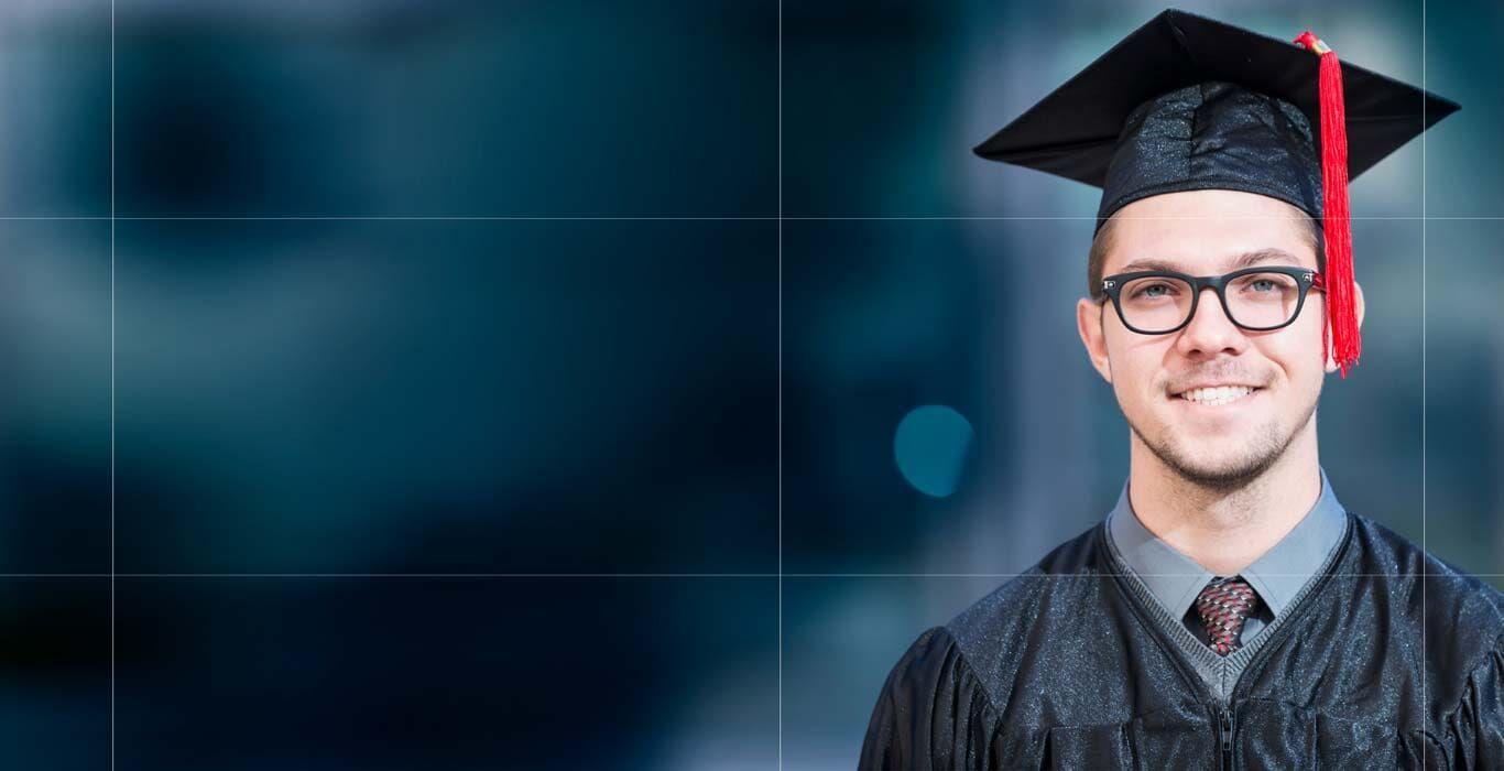 Un graduado sonriente con toga y birrete, que lleva gafas, sobre un fondo borroso de color verde azulado oscuro.