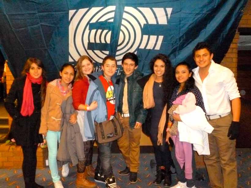 Un grupo de ocho personas posan sonrientes frente a una pancarta azul con un diseño circular blanco, para una foto de grupo.
