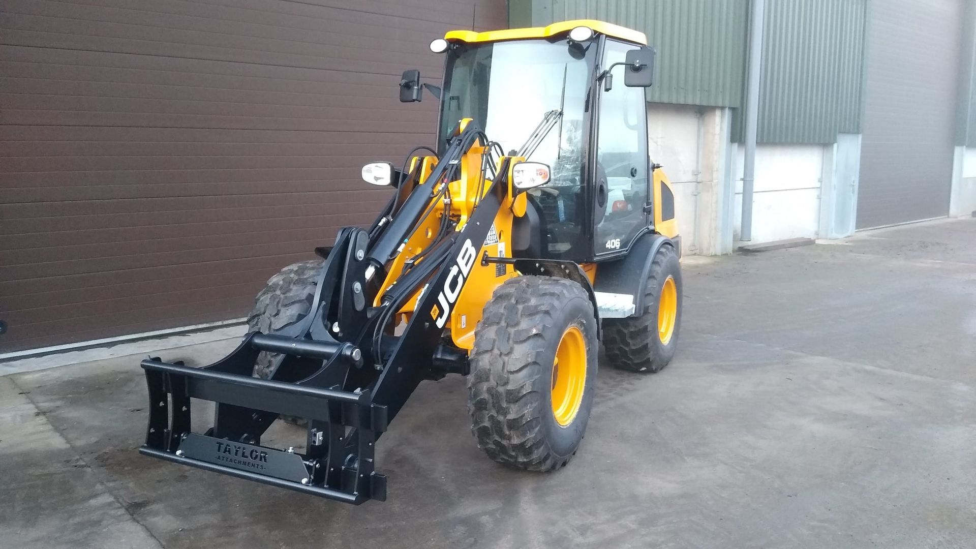A yellow and black jcb tractor is parked in front of a building