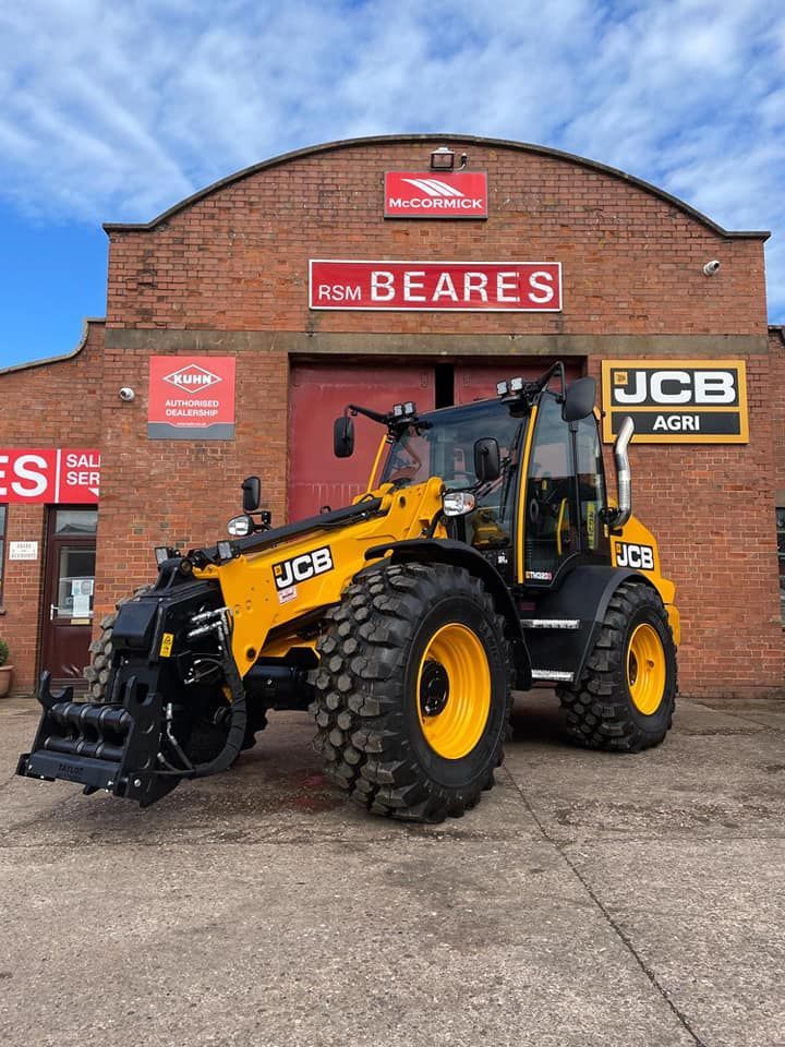 A yellow and black tractor is parked in front of a brick building.