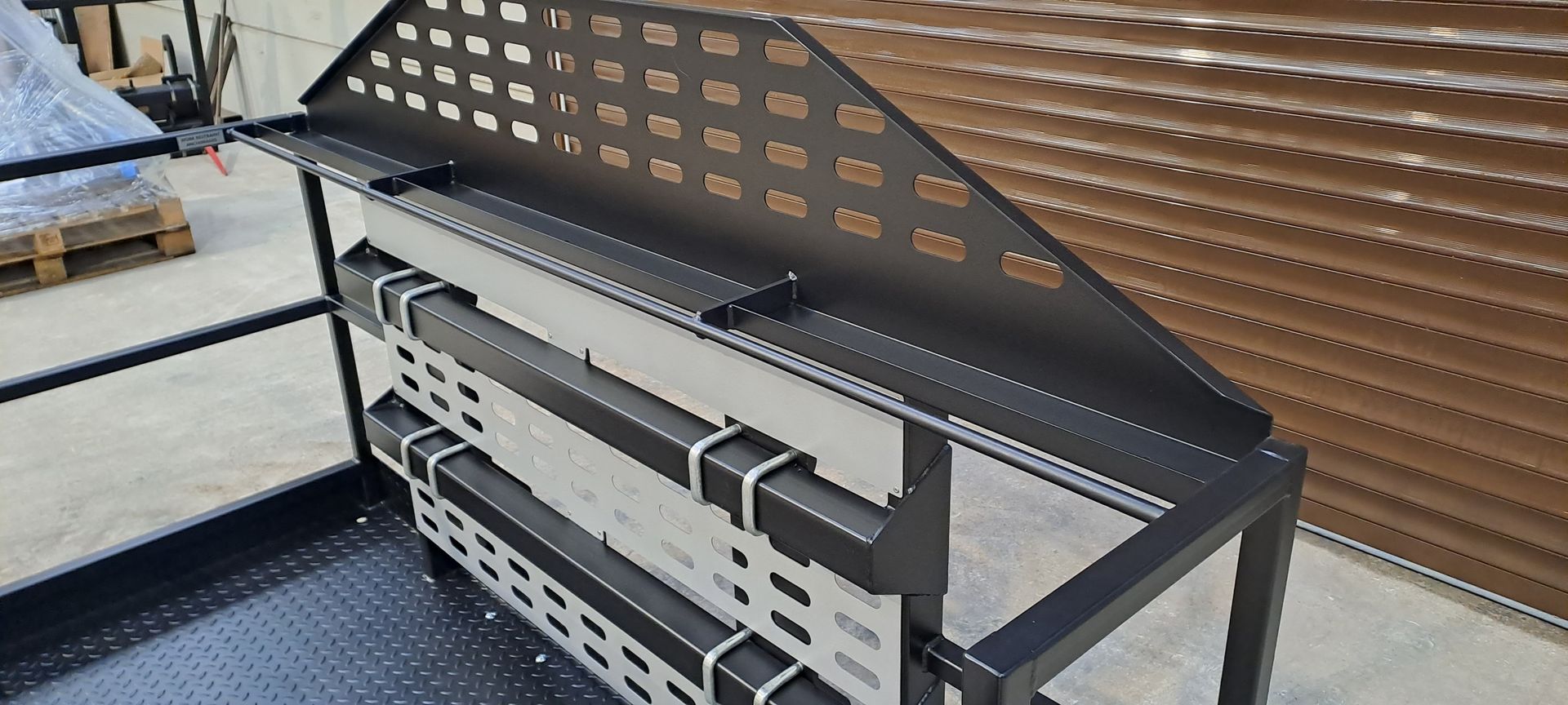 A metal shelf with a roof is sitting on the ground in a warehouse.