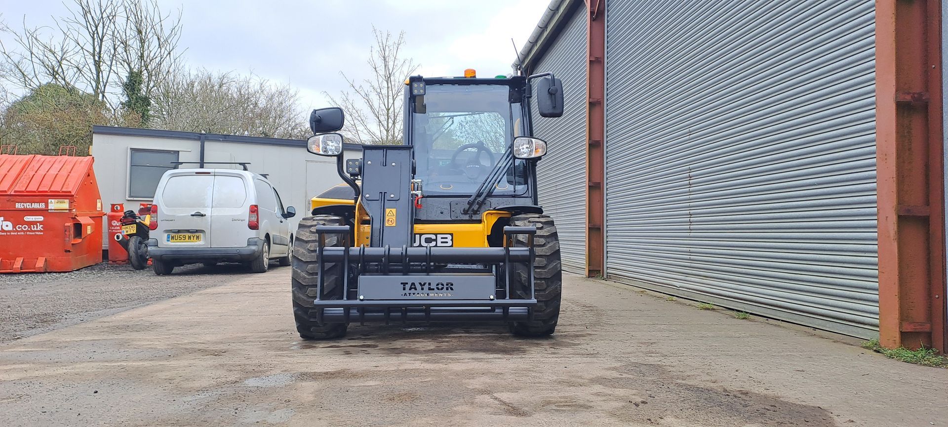 A yellow and black forklift is parked in front of a building.