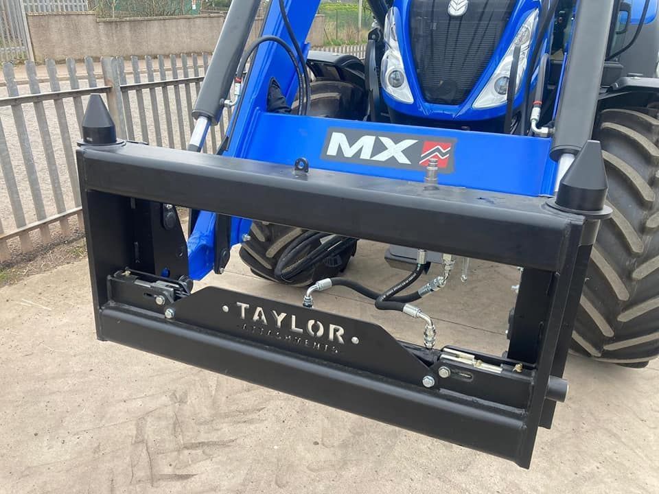 A blue tractor with a forklift attached to it.