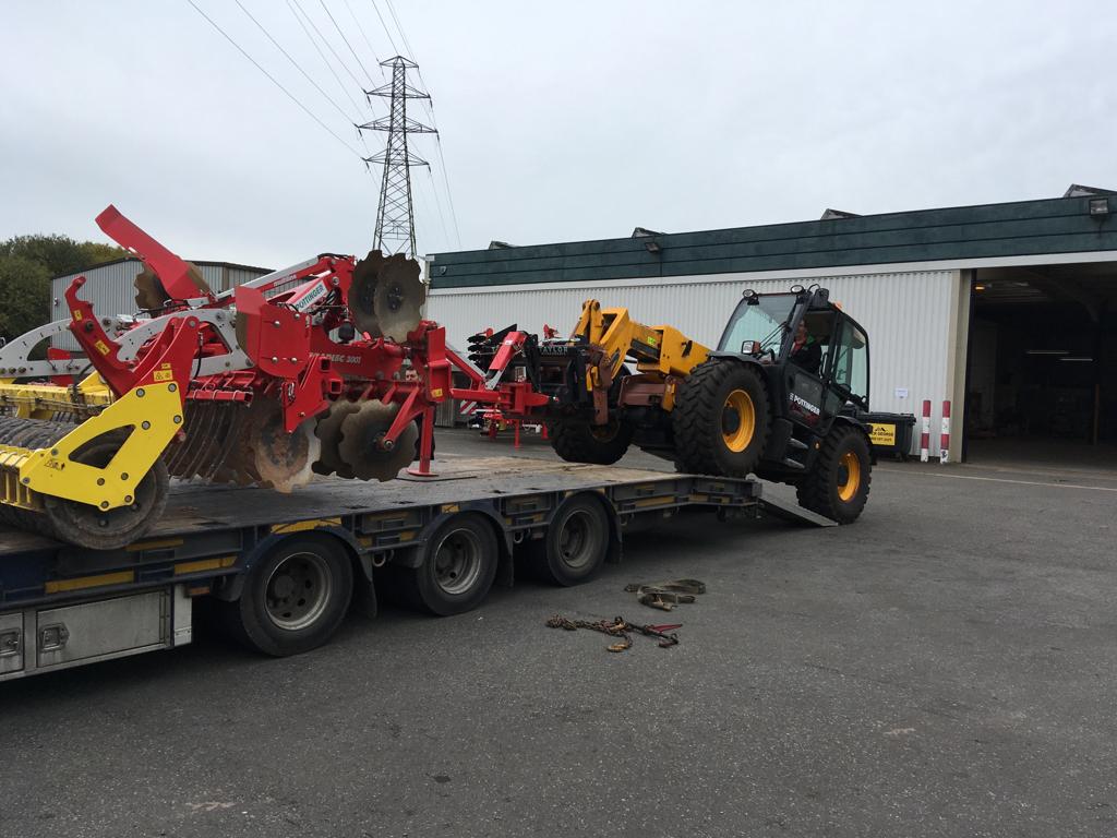 A red and yellow tractor is sitting on top of a trailer.