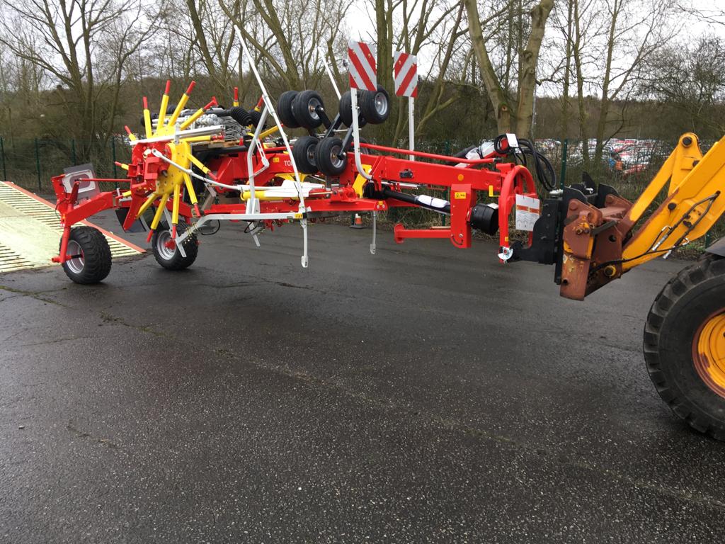 A red and yellow tractor is parked on the side of the road next to a yellow tractor.