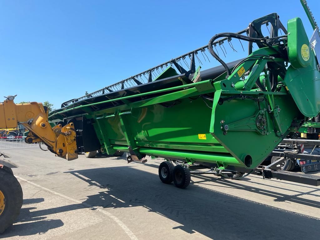A green tractor is parked in a parking lot next to a yellow tractor.