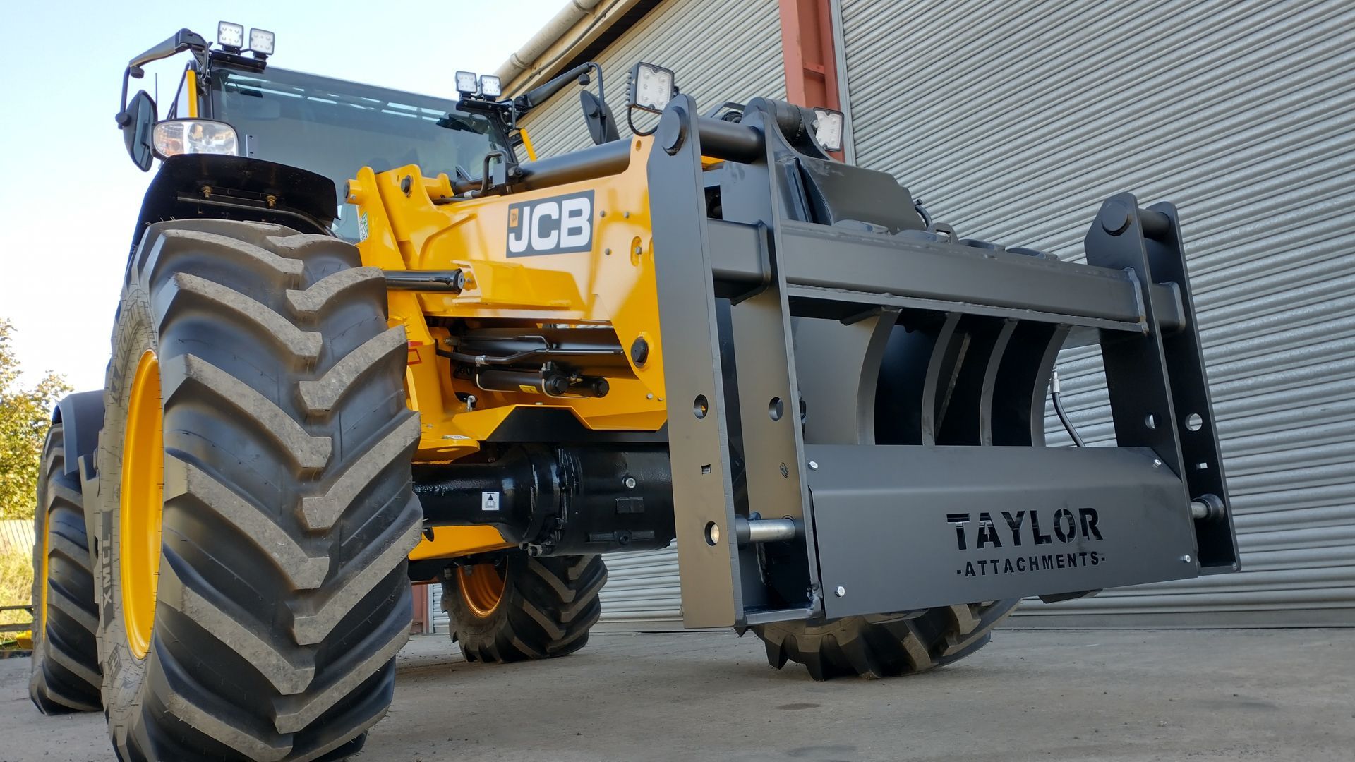 A yellow jcb tractor is parked in front of a building
