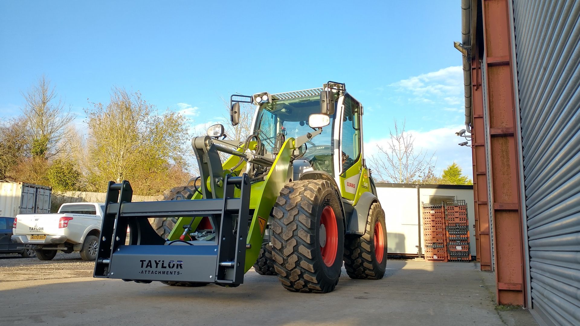 A tractor with a forklift attached to it is parked in front of a building.