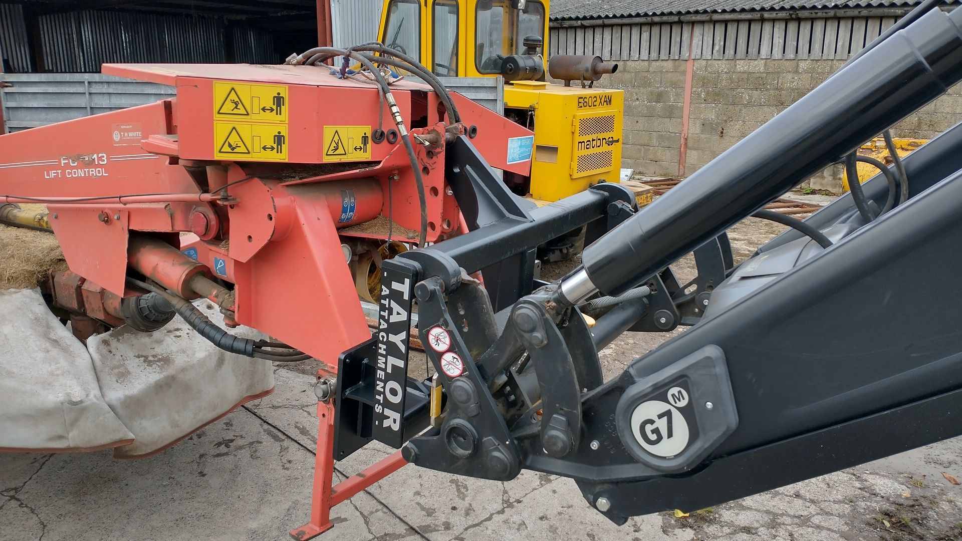 A red and black tractor is parked on the side of the road.