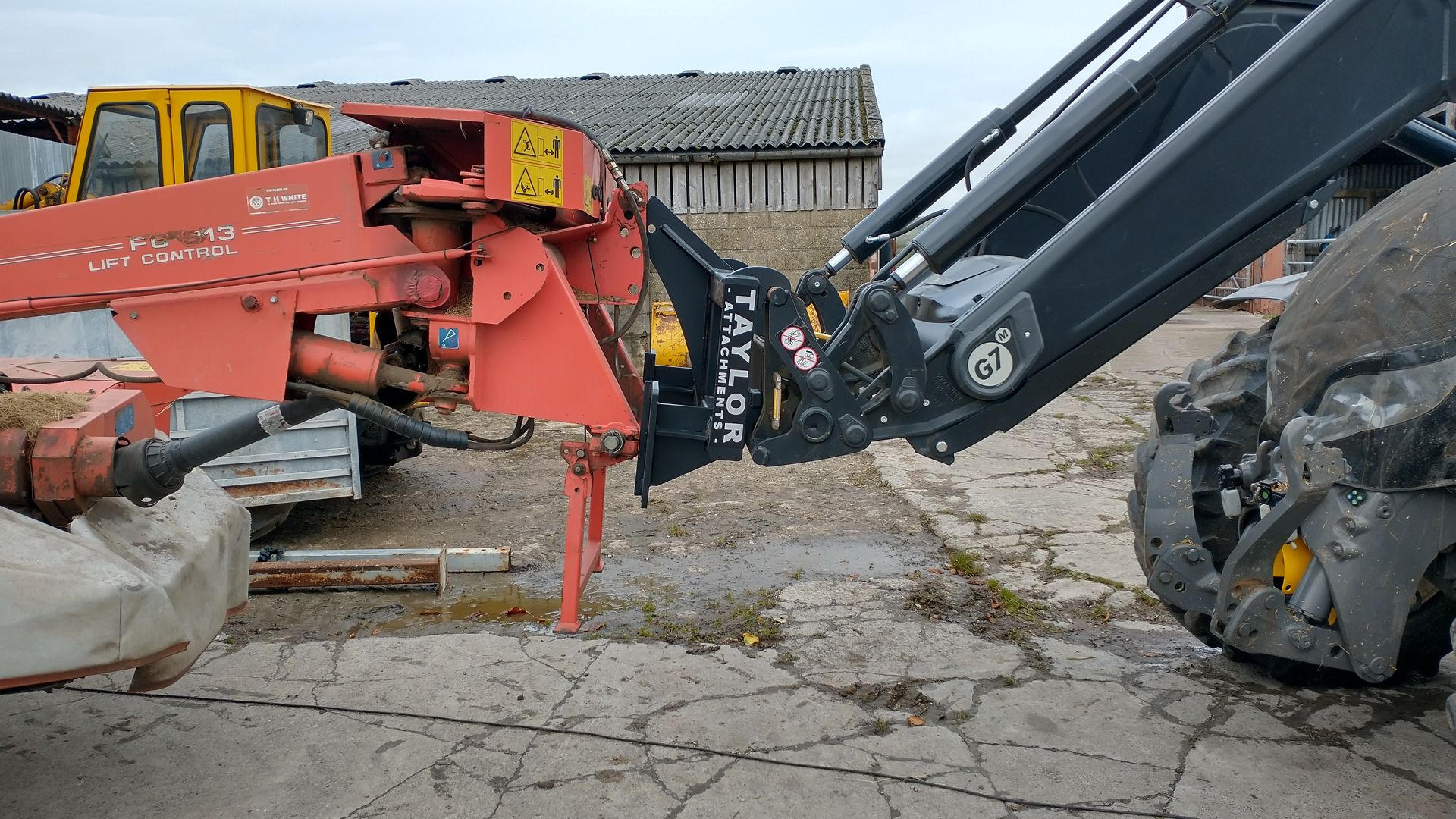 A red tractor is parked next to a black tractor.