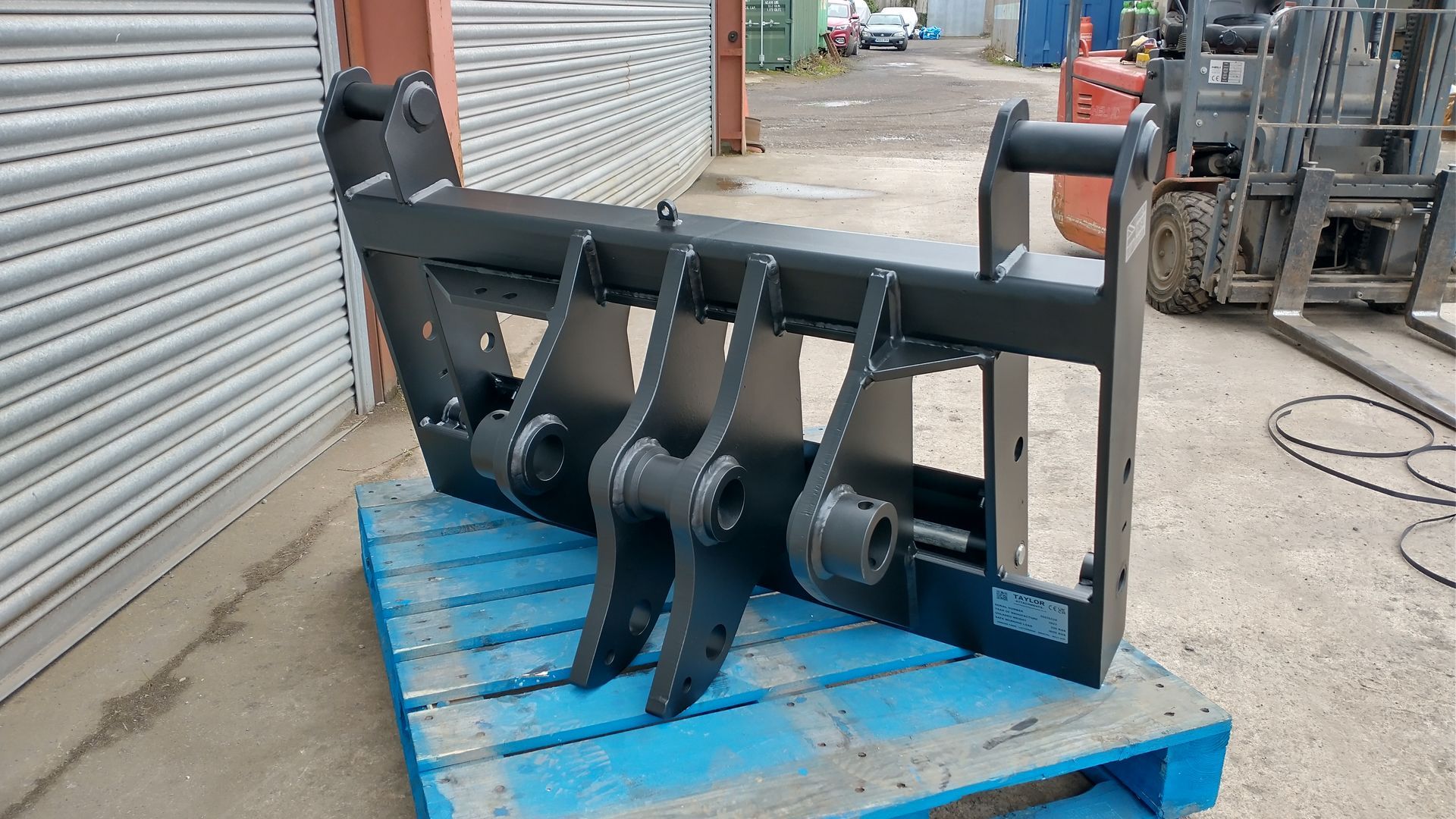 A forklift attachment is sitting on top of a blue pallet.