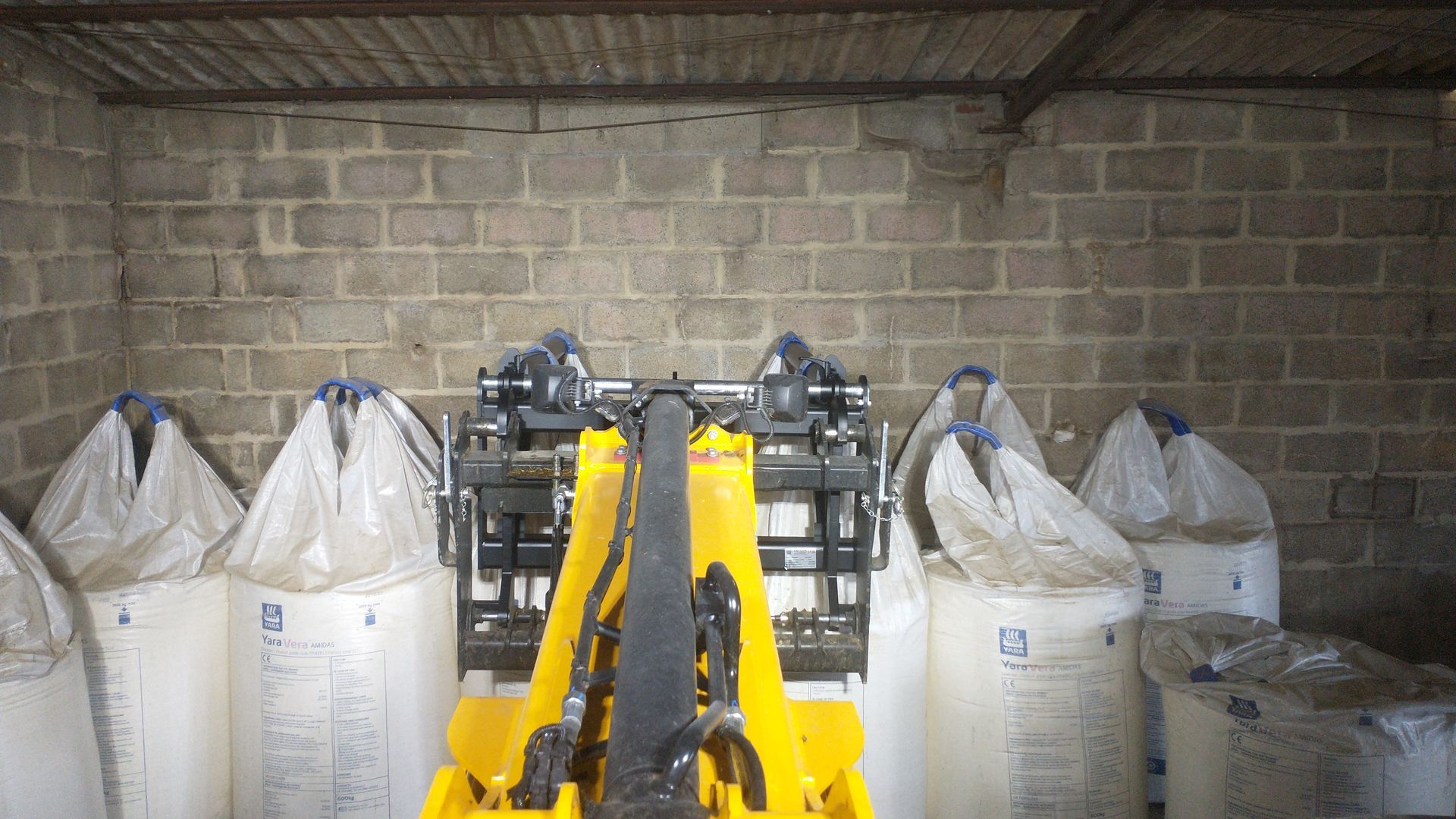 A yellow forklift is sitting in a warehouse filled with bags.
