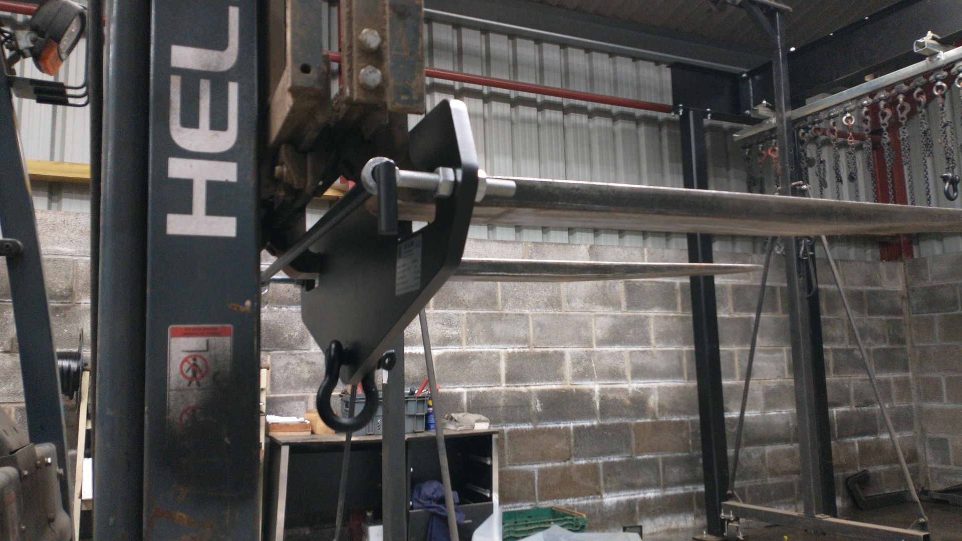A hel forklift is sitting in a warehouse next to a brick wall.