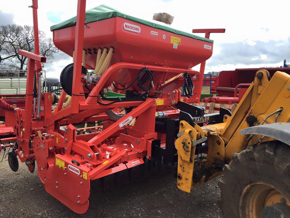 A red tractor is parked next to a yellow tractor.