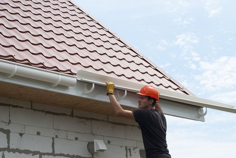 male worker installing roof gutter