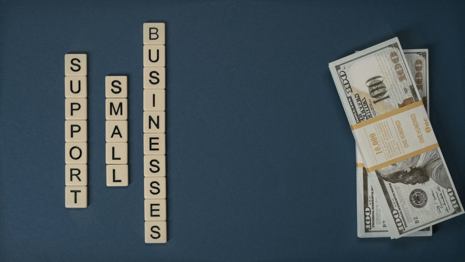 A stack of money next to a sign that says support small businesses