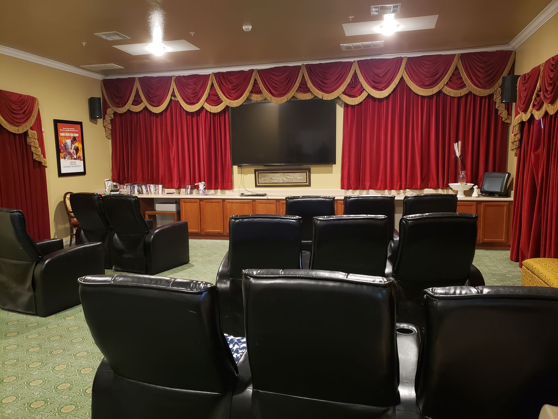 A movie theater with black chairs and a large flat screen tv.