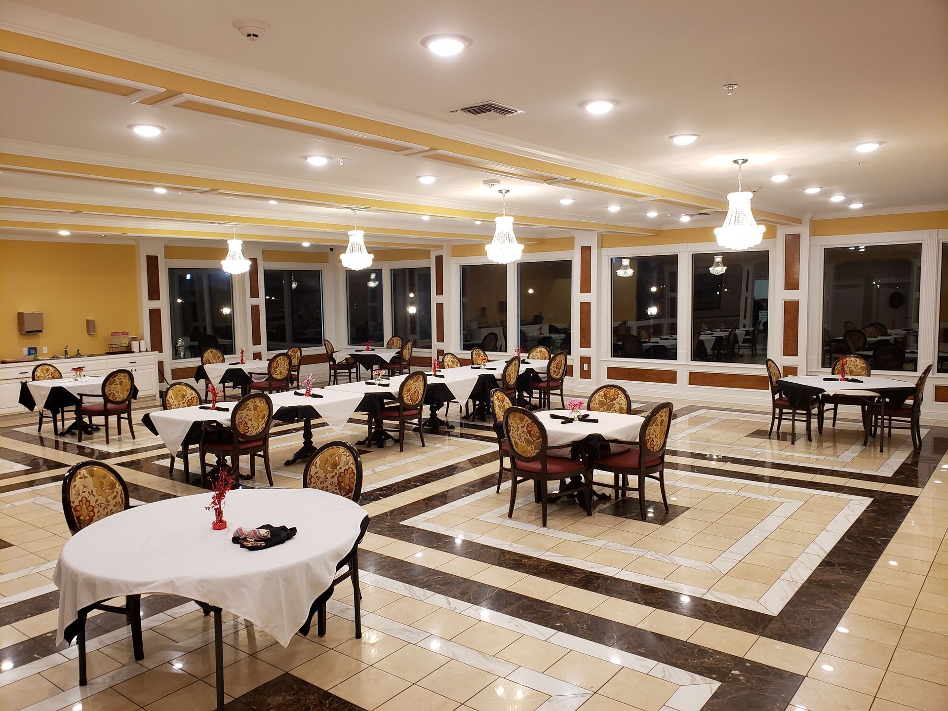 A large dining room with tables and chairs and a tiled floor.