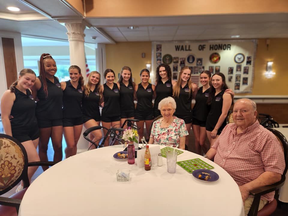 A group of people are posing for a picture in front of a wall of honor