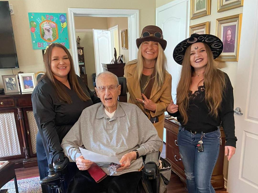 A group of people are standing around a man in a wheelchair.