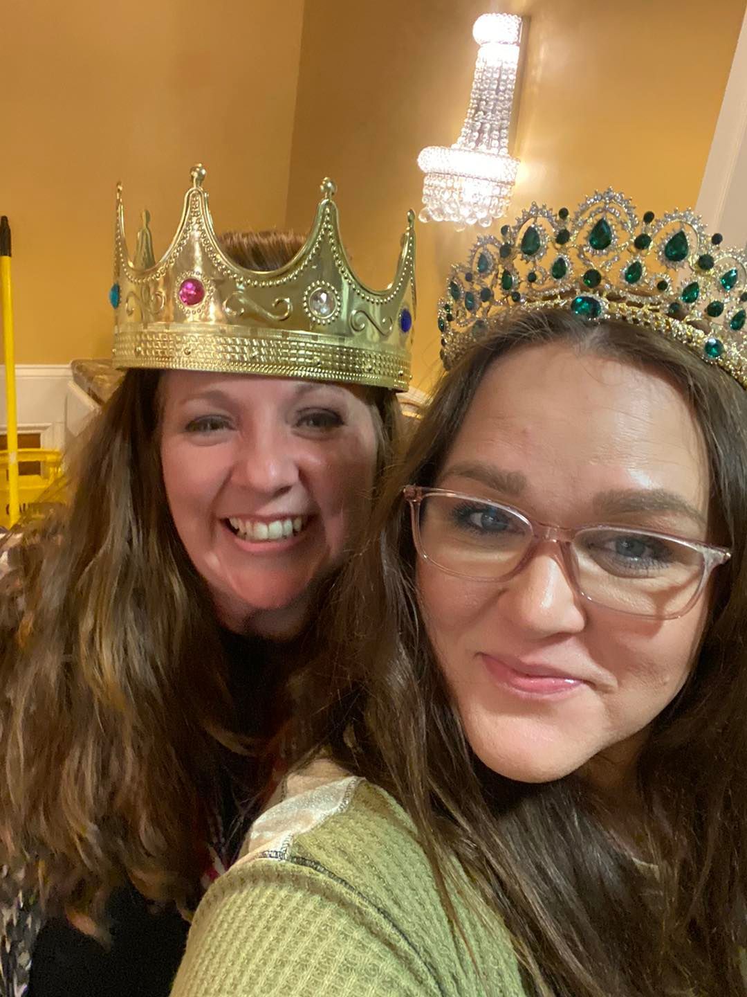 Two women wearing crowns and glasses are posing for a picture.