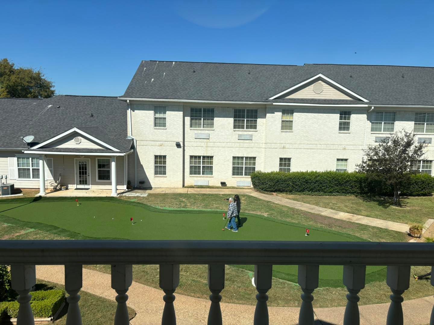 A man is playing golf in front of a large white building.
