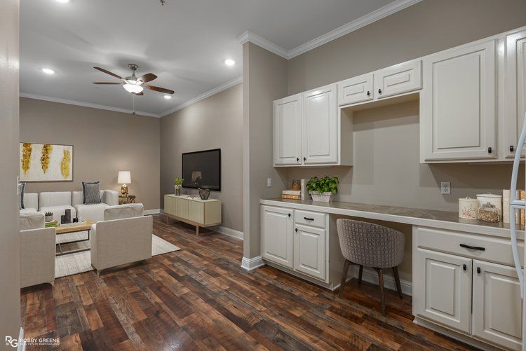 A living room and kitchen in a house with hardwood floors and white cabinets.