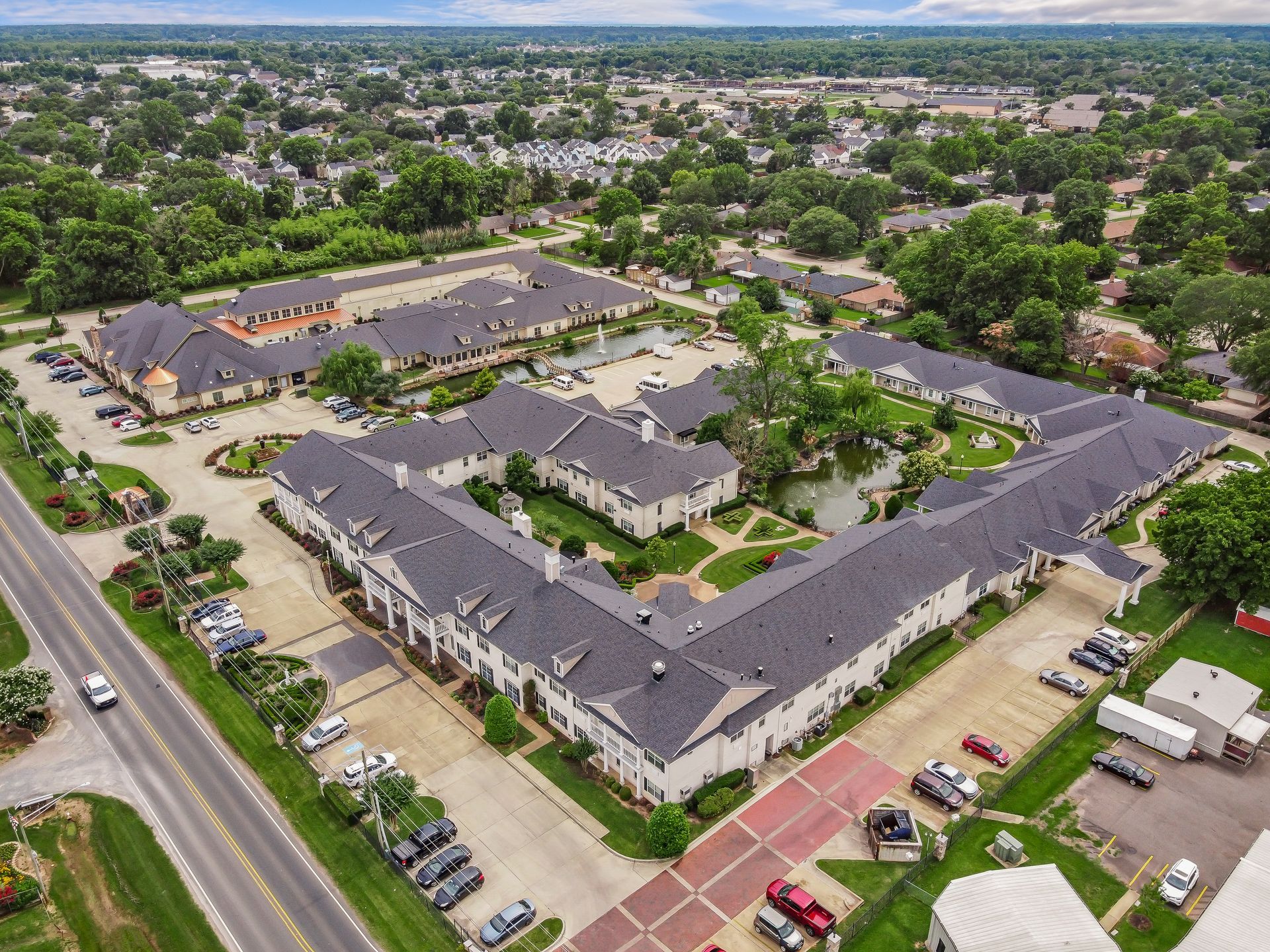 An aerial view of a large apartment complex with a lot of cars parked in front of it.