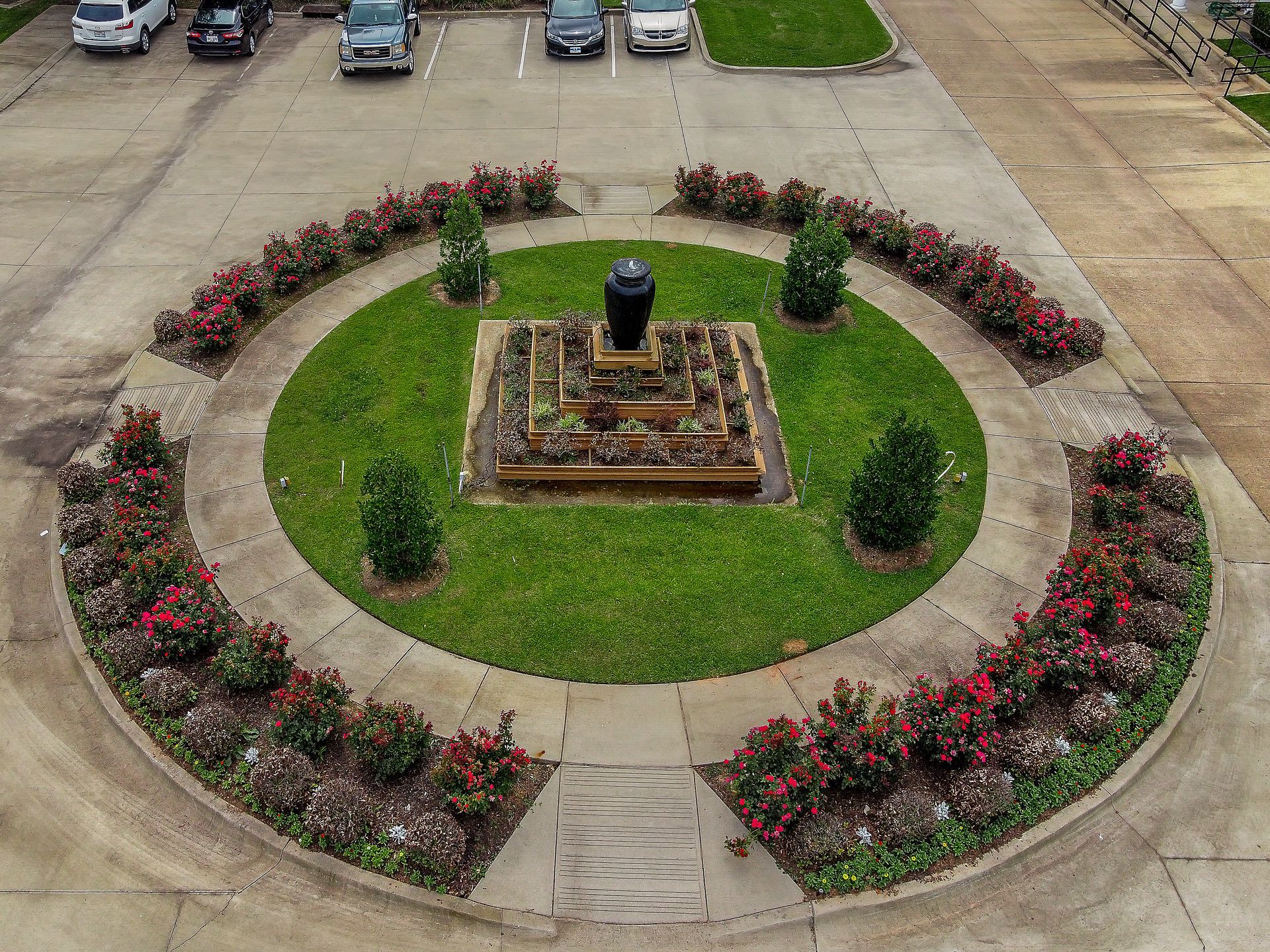 An aerial view of a circular garden with a fountain in the middle.