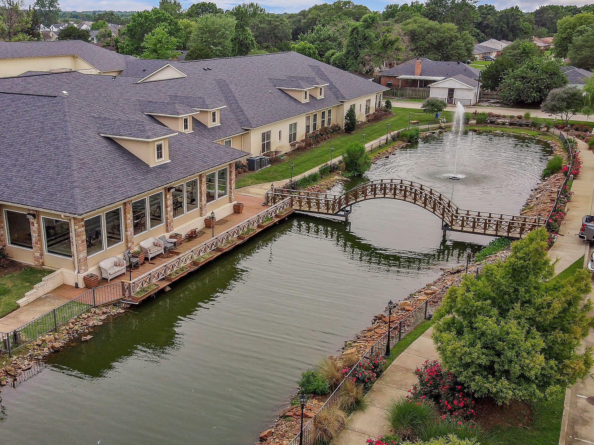 An aerial view of a large house with a pond in front of it.