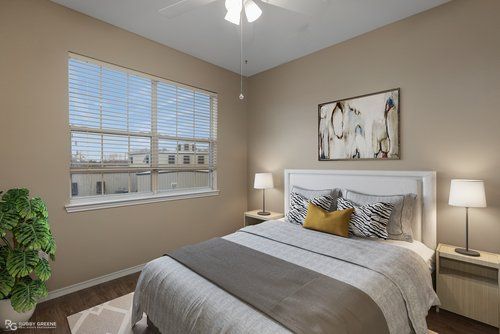 A bedroom with a bed , lamps , a window and a ceiling fan.